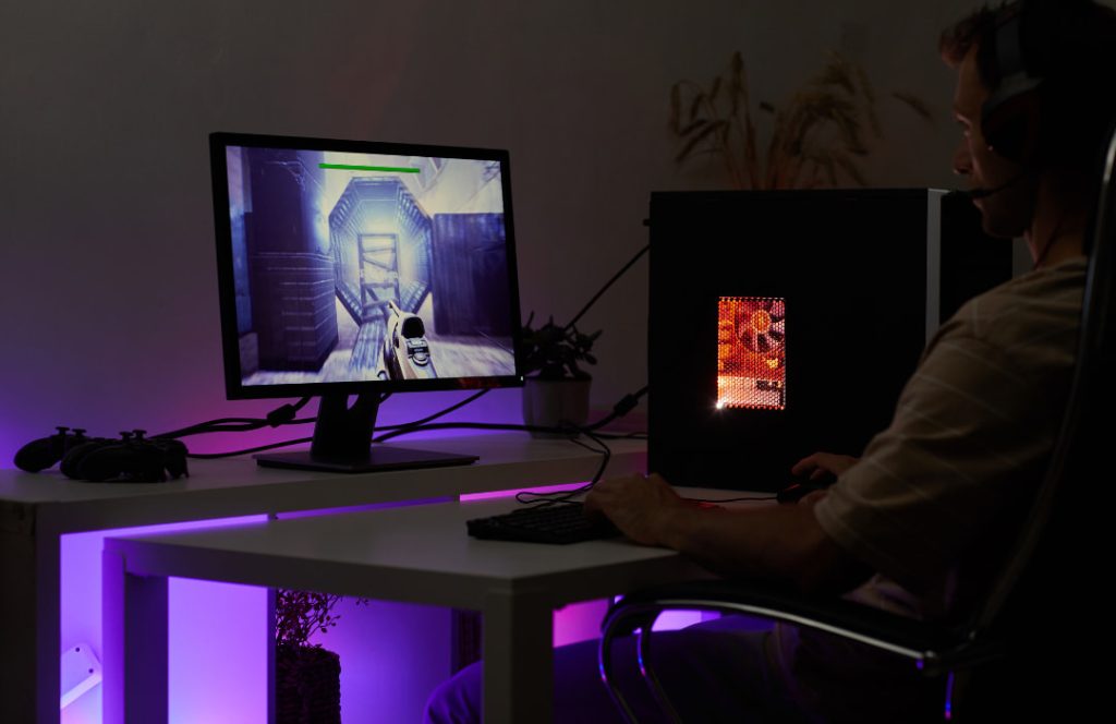 Quarto gamer com mesa, computador e luzes de led.